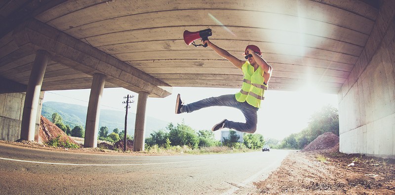 Man in geel hesje springt gat in de lucht